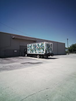 A vibrant delivery truck parked at a warehouse loading dock under a clear sky in Maitland, FL.