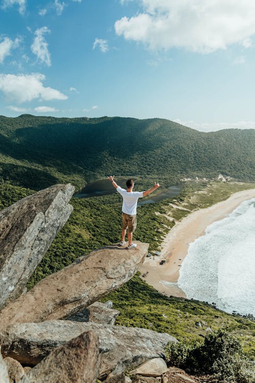 Man Standing on a Cliff Near a Body of Water