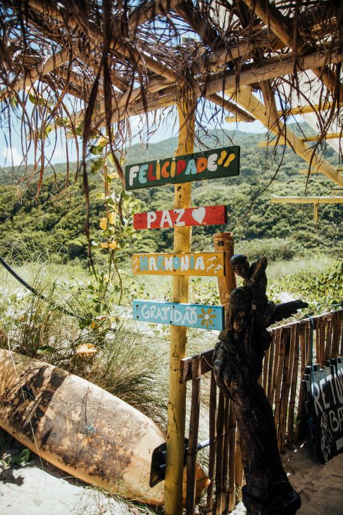 Free Colorful wooden signpost under a thatched roof, surrounded by lush greenery in Brazil. Stock Photo