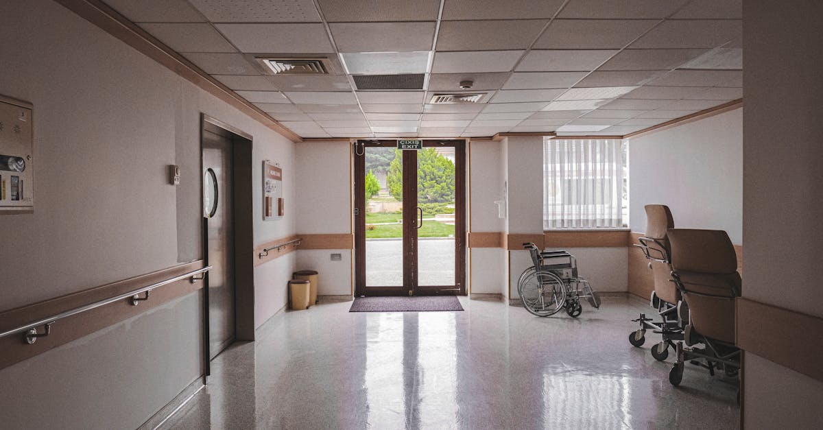 Photo by Zakir Rushanly Hospital corridor with wheelchair, reflecting glass doors, and outdoor view. Ideal for healthcare themes.