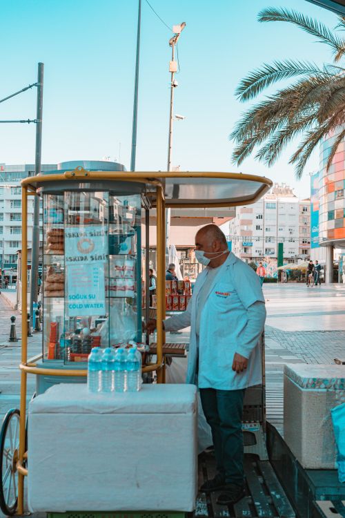 Free Street vendor offers bottled water and snacks from a mobile cart in a bustling city. Stock Photo
