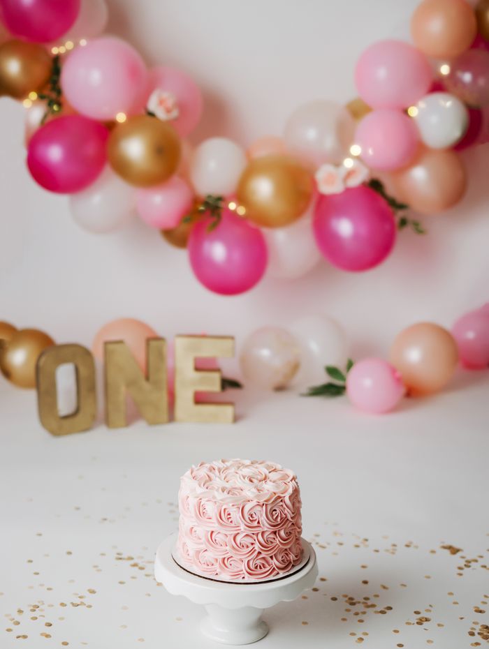 Pink birthday cake with balloon backdrop