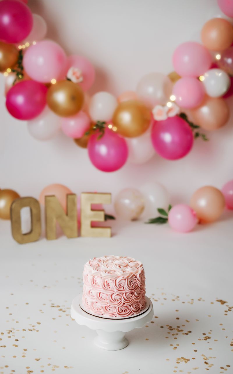 Pink birthday cake with balloon backdrop