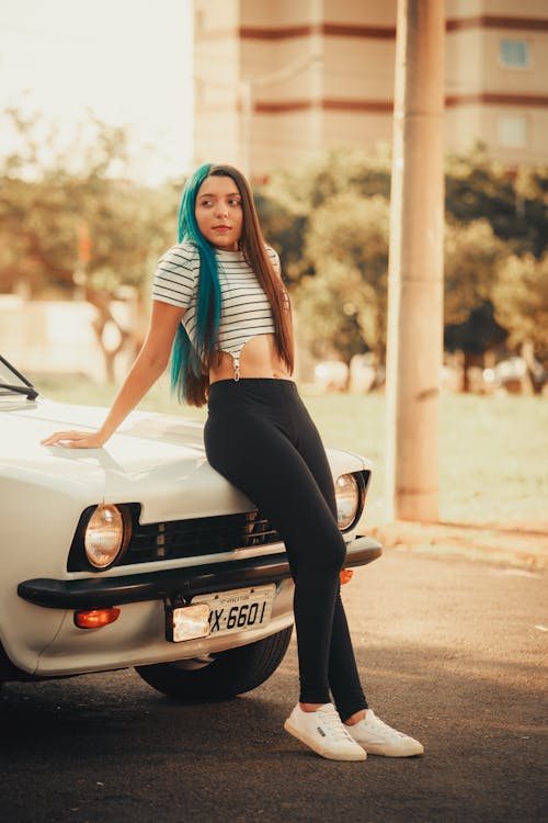 Woman in a Striped Shirt and Black Leggings Leaning on a White Car ...