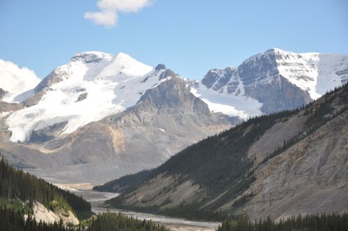 Free A stunning view of snow-capped peaks in a lush mountain valley under a clear sky. Stock Photo