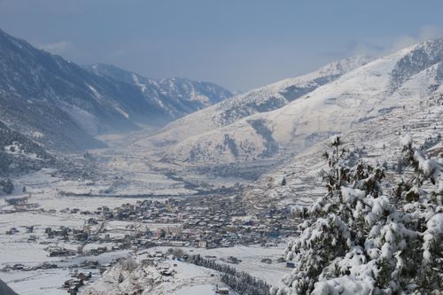 Free Scenic view of a snow-covered village surrounded by mountains in winter. Stock Photo