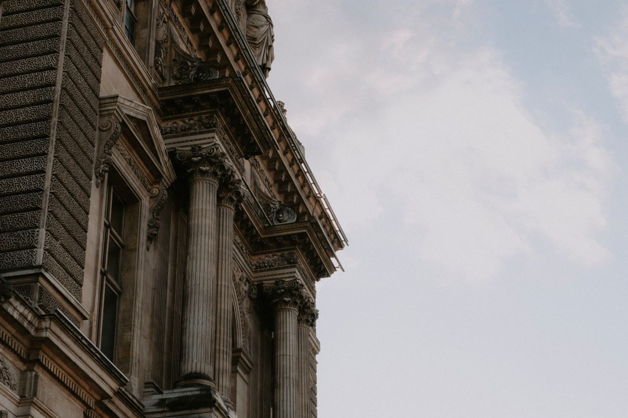 elegant architectural detail featuring ornate columns under a cloudy s