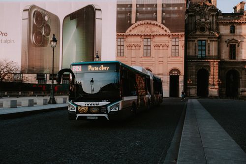 Free City bus on a cobbled street against historic architecture in urban setting, early evening. Stock Photo