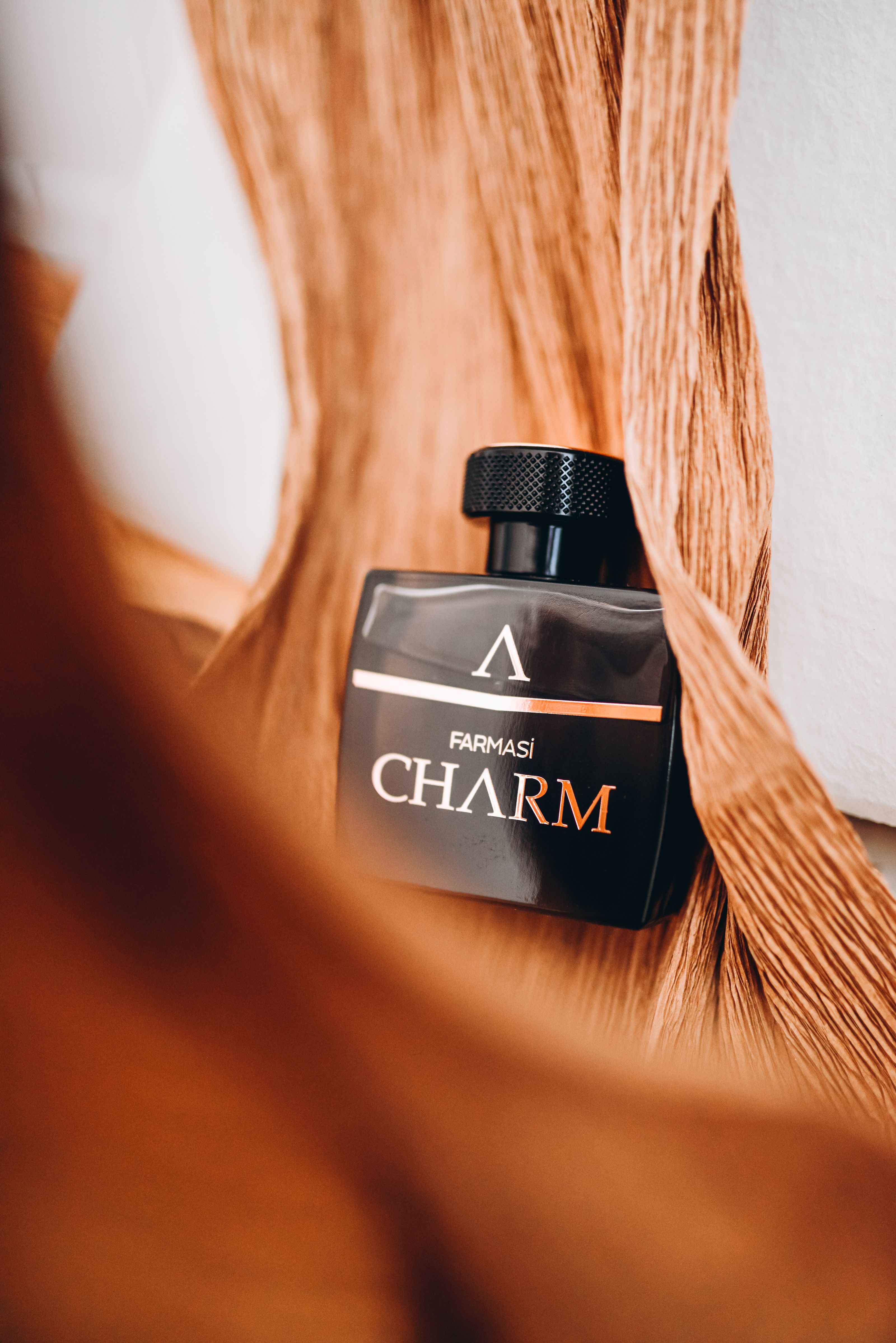 Close elegante de uma garrafa de perfume Farmasi Charm com composição artística.