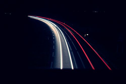 Free Dynamic long exposure shot of car light trails on a dark road at night. Stock Photo