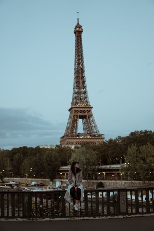 Woman Sitting on a Bridge Fence in front of the Eiffel Tower