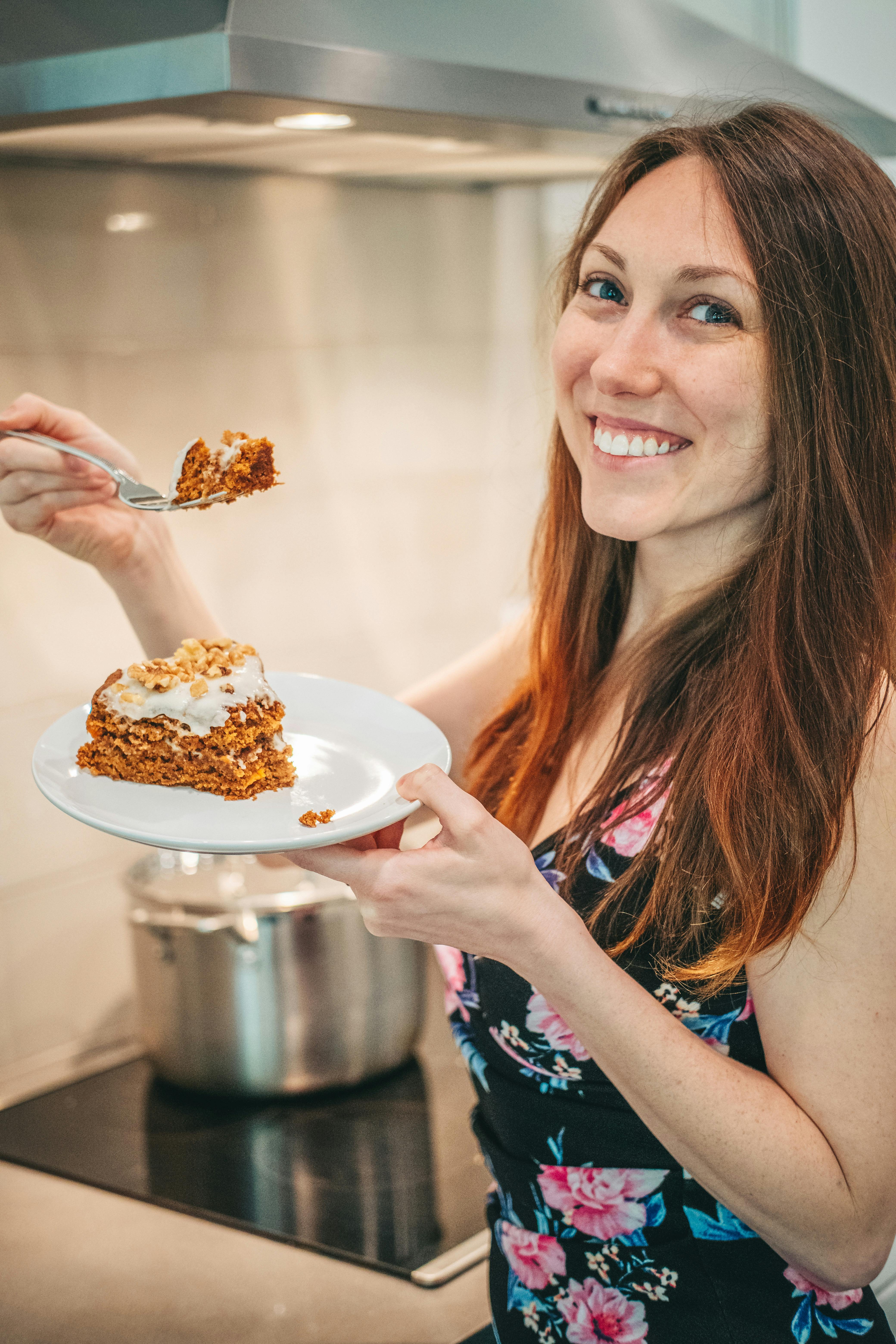 smiling woman holding a plate with a cake