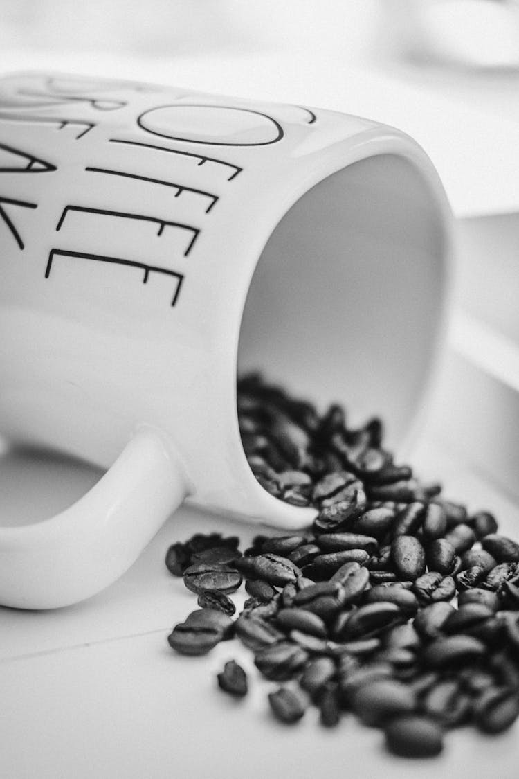 A Grayscale Of Spilled Coffee Beans From A Mug