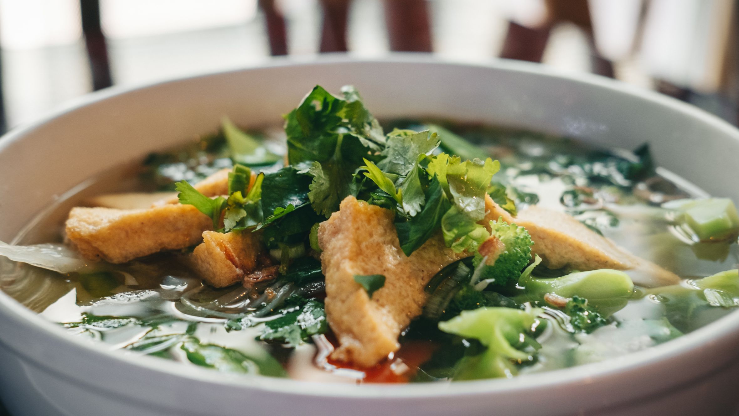 Delicious bowl of Vietnamese pho soup with tofu, herbs, and greens, perfect for food lovers.