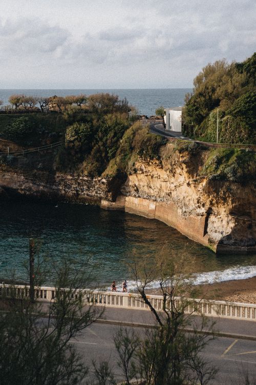 Free Breathtaking coastal scene with cliffs, lush greenery, and a winding road overlooking the sea. Stock Photo