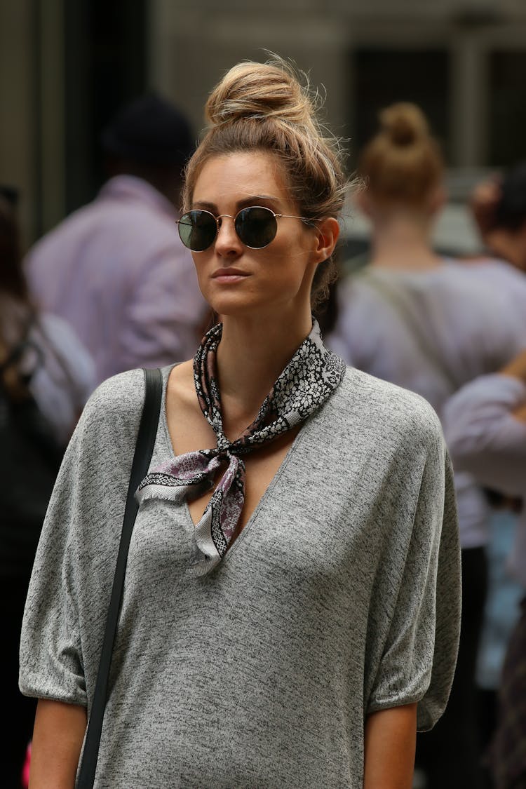 Blond Woman Wearing Gray Blouse And Neckerchief Standing On Street