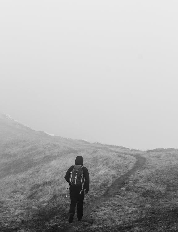 Grayscale Photo of a Person Trekking