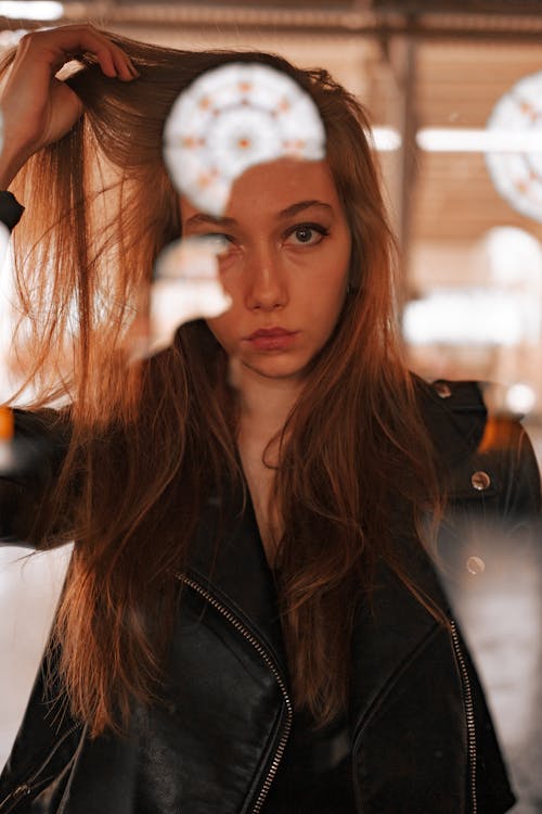 Woman in Black Leather Jacket Touching Her Hair