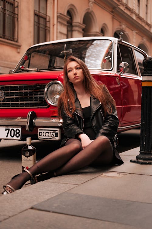 A Woman Sitting by a Vintage Car