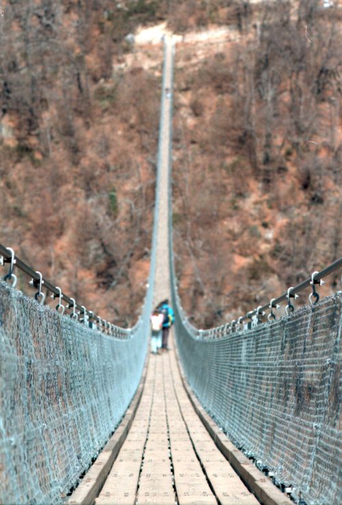 Free People crossing a scenic suspension bridge in Bellinzona, Switzerland during a sunny day. Stock Photo