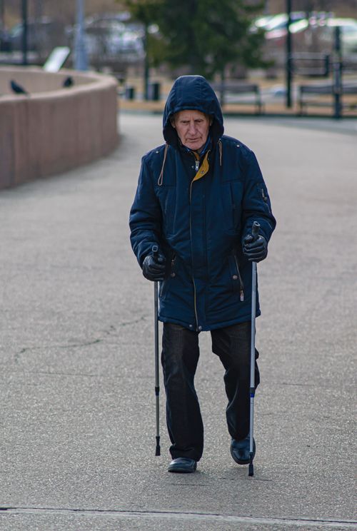 Free Elderly man practicing nordic walking on a city sidewalk during daytime. Stock Photo