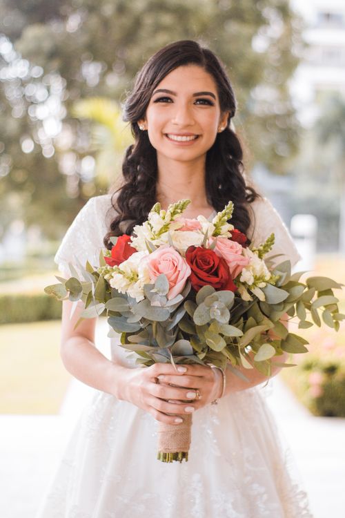 Free Smiling bride holding a vibrant floral bouquet in an outdoor setting. Perfect representation of joy and elegance. Stock Photo