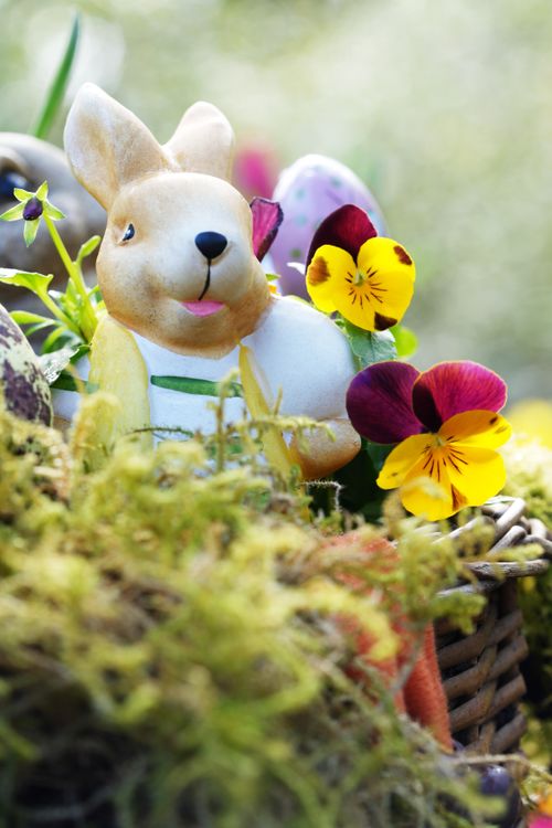 Free Ceramic Easter bunny surrounded by colorful flowers and Easter eggs in a vibrant spring setting. Stock Photo