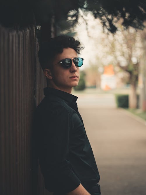 Portrait of a Man with Black Sunglasses Near a Fence