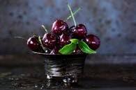 一个质朴的金属碗里，盛满了新鲜多汁的樱桃，还带着水汽