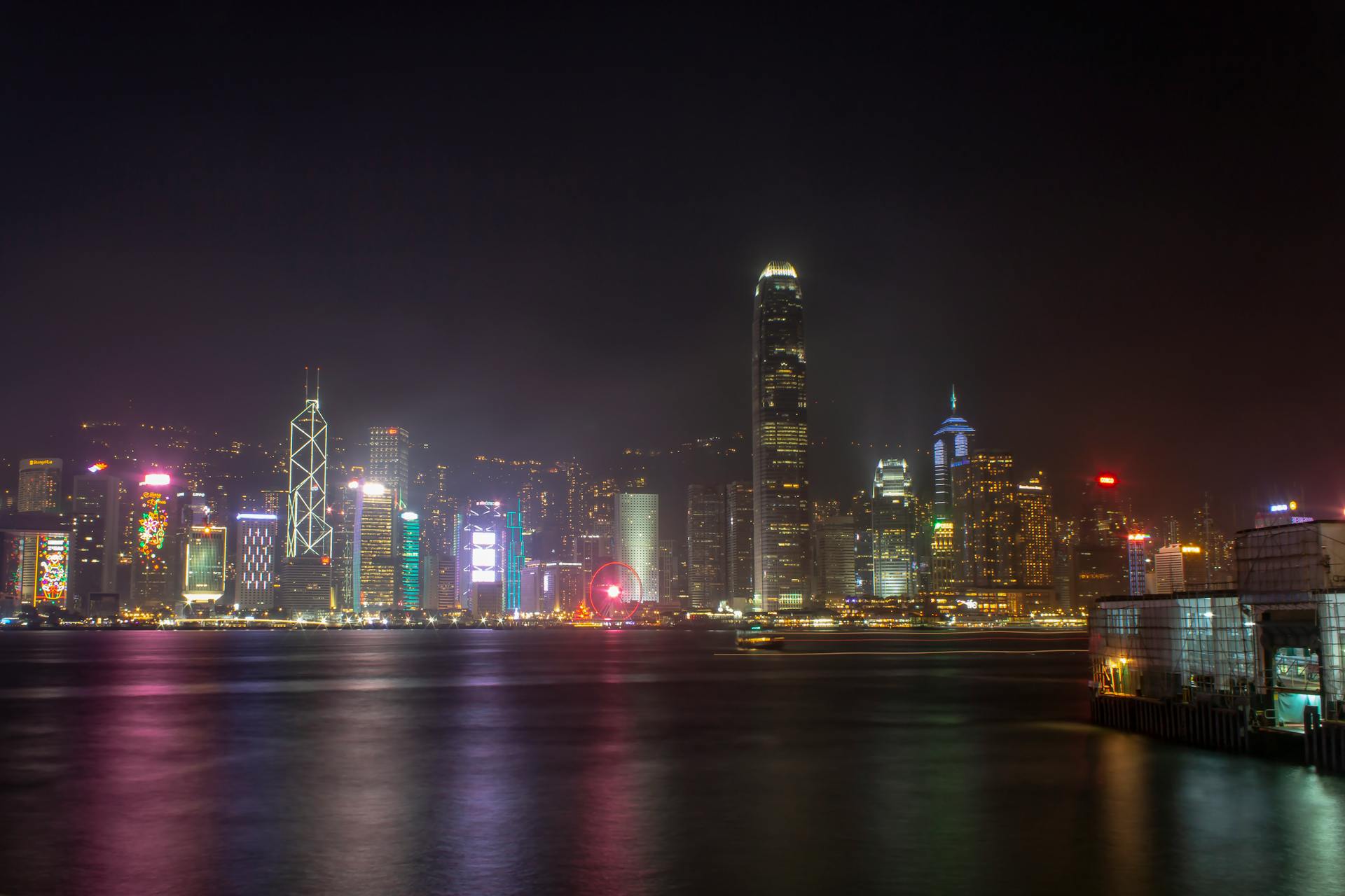 Illuminated Hong Kong skyline at night with vibrant skyscrapers reflected on Victoria Harbour.