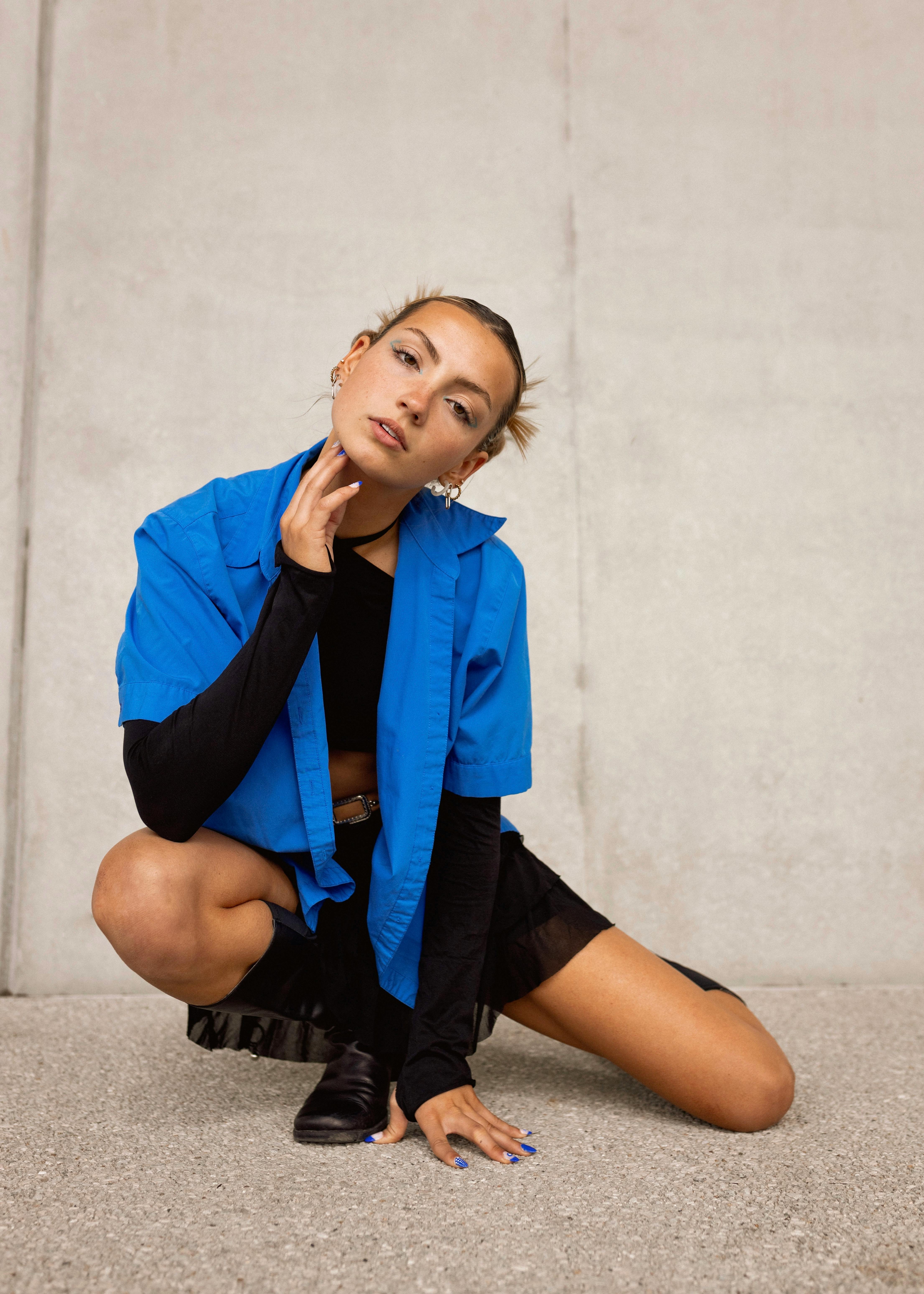 Elegant young woman posing stylishly against a concrete backdrop, showcasing modern fashion.