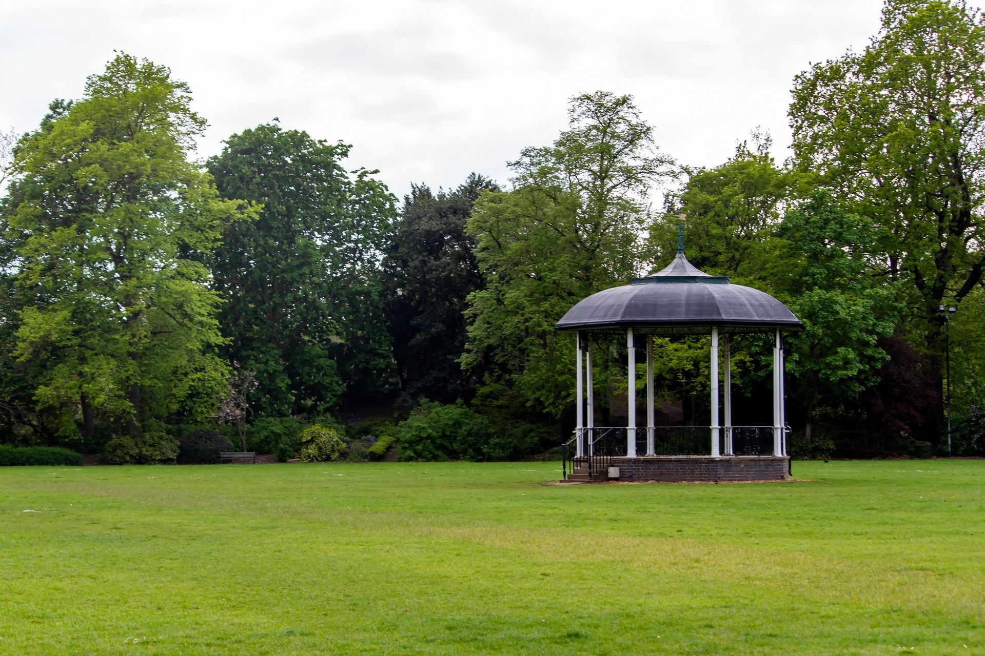 A scenic summer park with an elegant gazebo surrounded by lush green trees, perfect for relaxation.