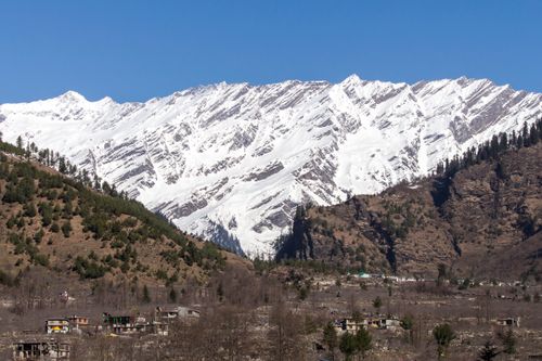 Free Picturesque mountain landscape featuring snowy peaks and a valley with scattered houses. Stock Photo