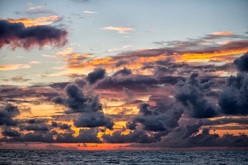 Free Stunning sunset over the ocean with vibrant colors and dramatic cloud formations. Stock Photo