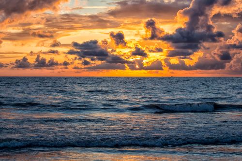 Free Stunning sunset over the ocean with a dramatic sky full of vibrant clouds. Stock Photo