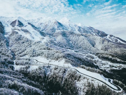 Mountains Covered in Snow Under Cloudy Sky