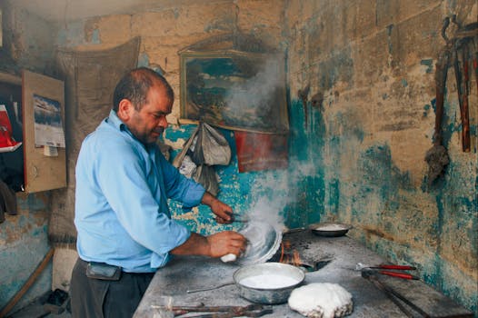 Artisan baker preparing flatbread in a rustic, smoky kitchen, emphasizing traditional methods.