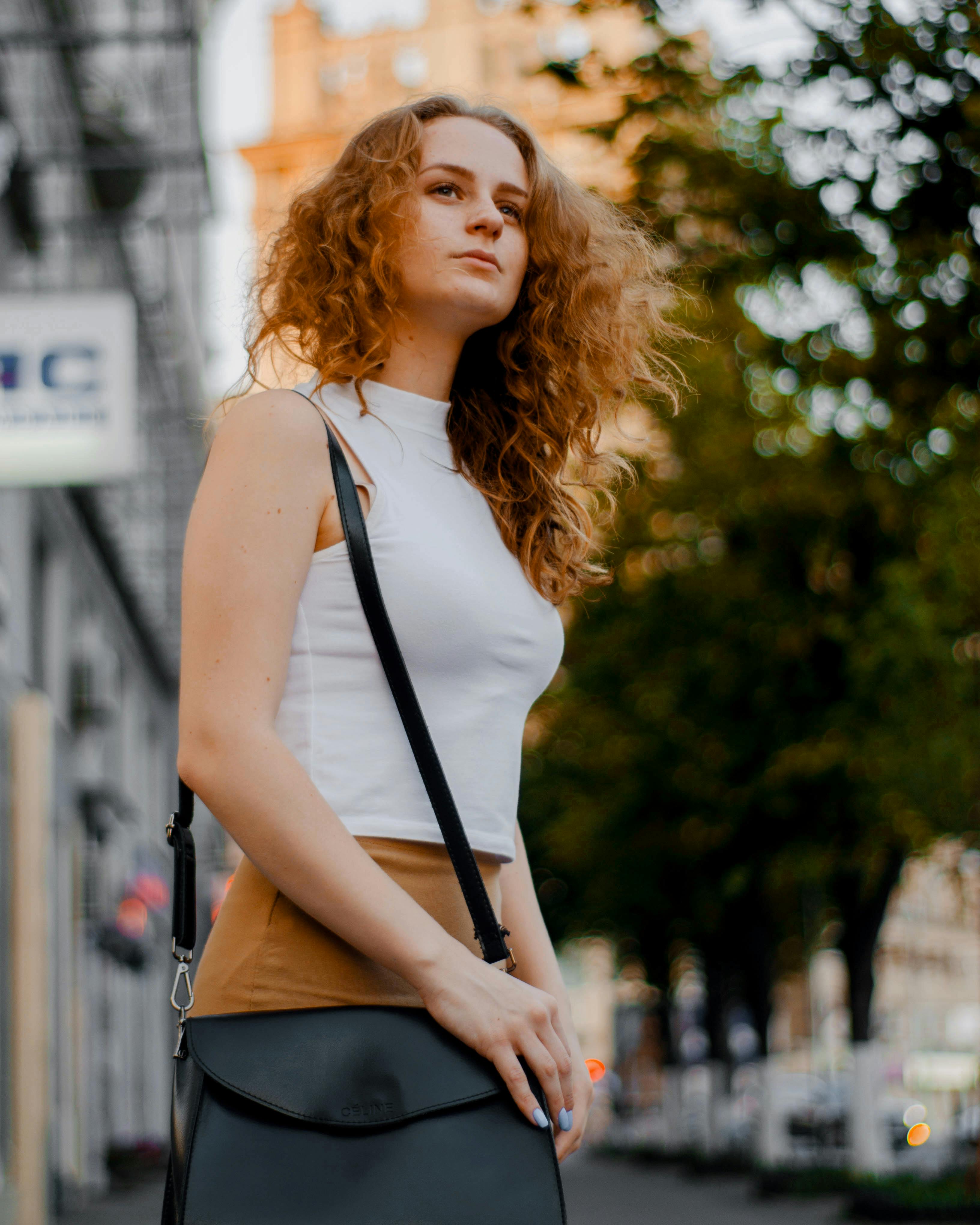 Woman in White Turtleneck Sleeveless Top and Brown Bottoms Holding Black  Leather Crossbody Bag Outfit · Free Stock Photo