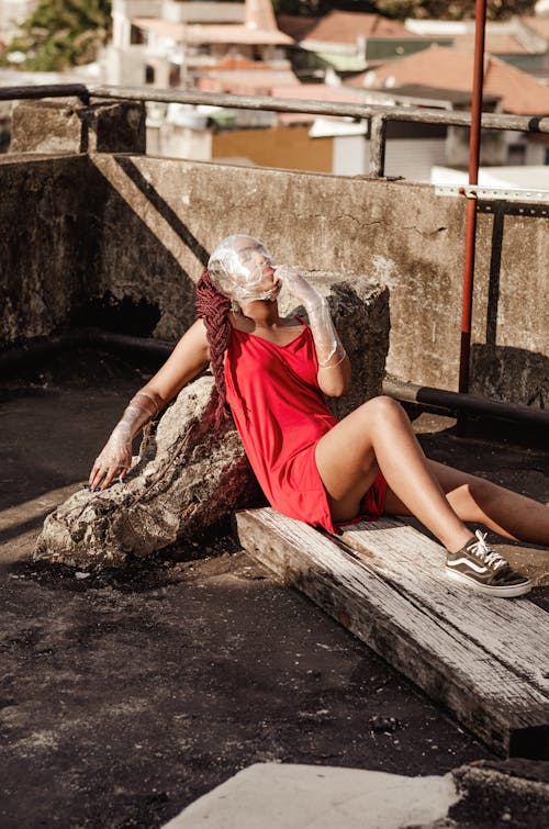 Free Woman in Red Dress Sitting on Brown Wooden Bench Stock Photo