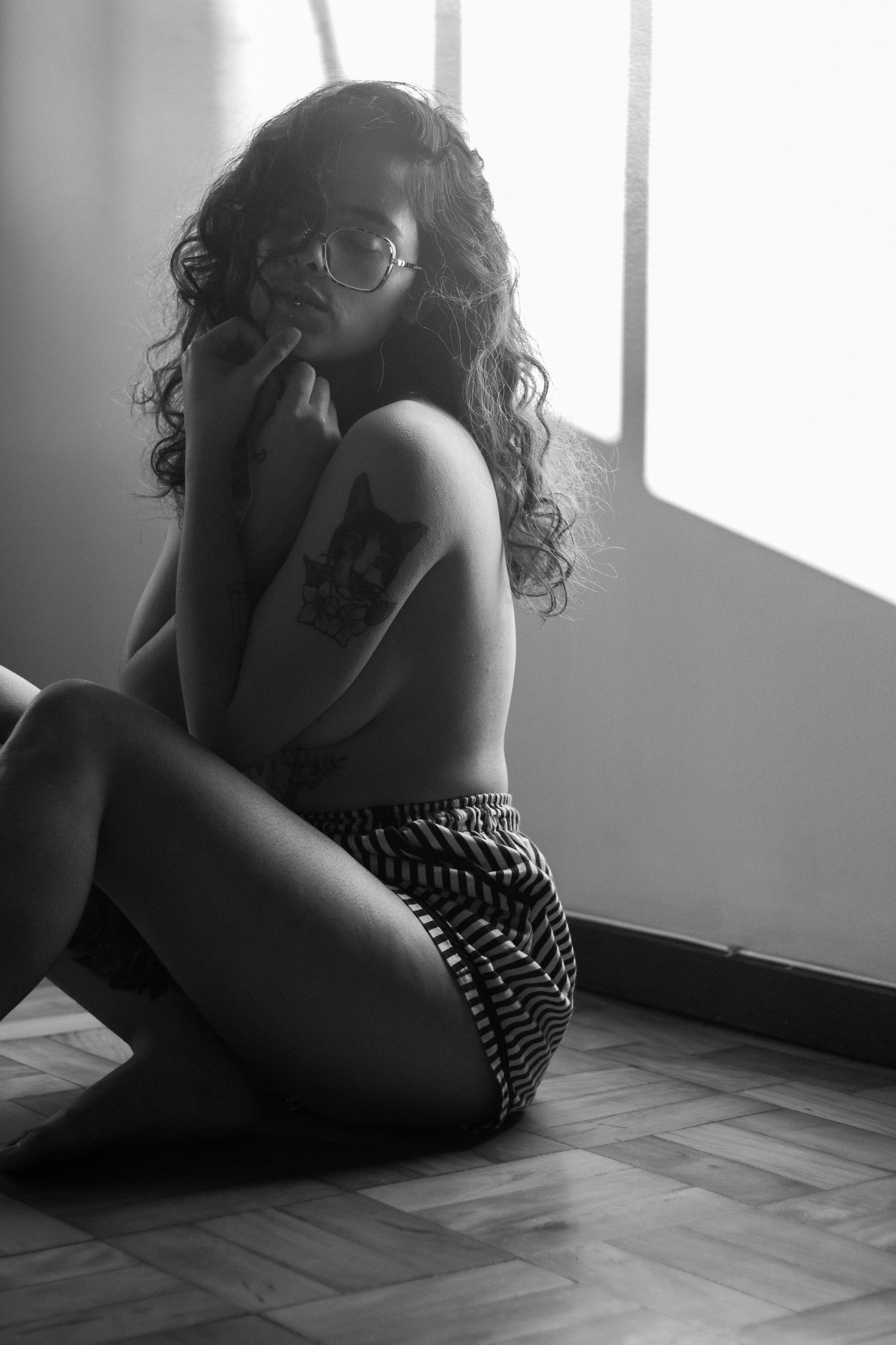 Monochrome Photo of a Shirtless Woman Sitting on the Floor