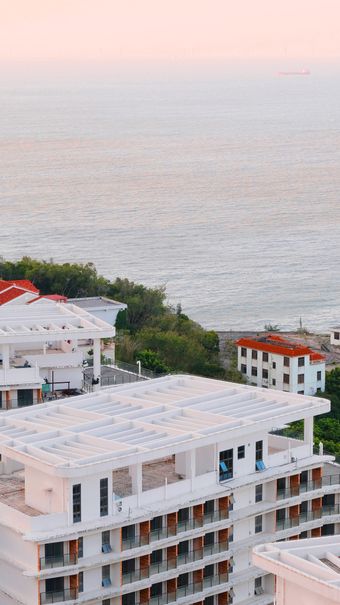 White seaside residences above a calm shoreline. Photo: chen pincheng on Pexels