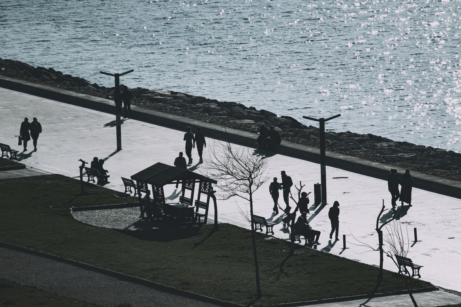 People walking a seafront promenade beside the water, photo by Halil Boybay on Pexels