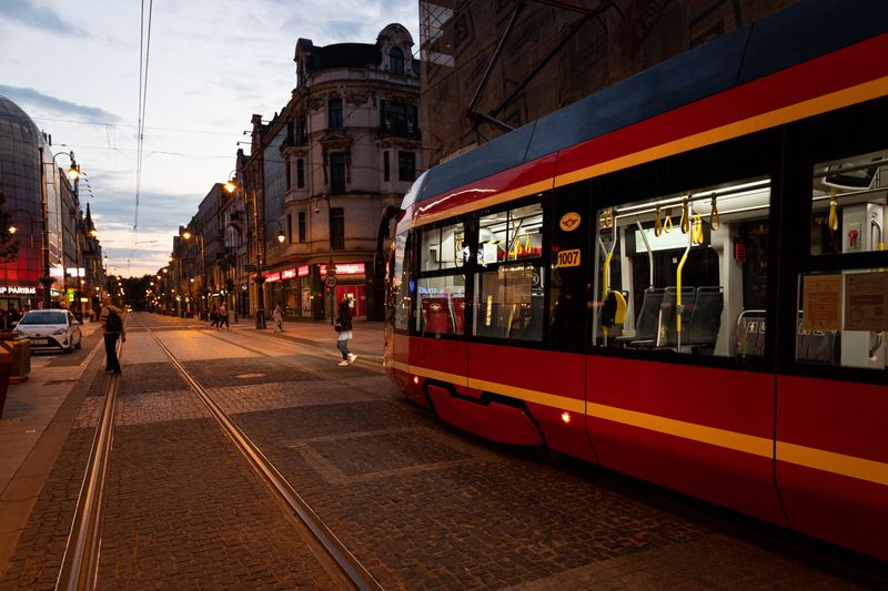 City street featuring a modern tramway during twilight with historic buildings.