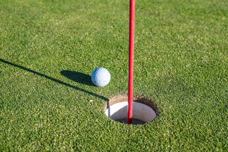 Close-Up Photo Of A Golf Ball Near A Hole