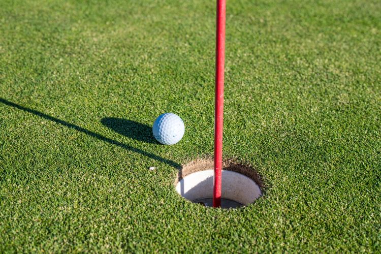 Golfbal vlak naast de hole met rode vlag op de green.