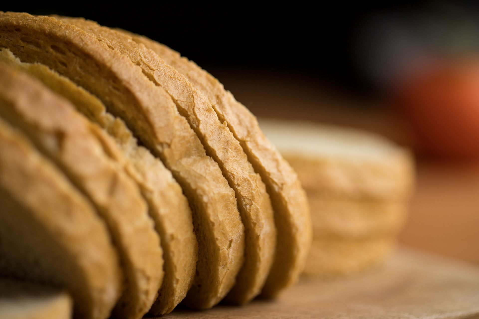 Detailed view of sliced artisan bread with golden crust on wooden board.