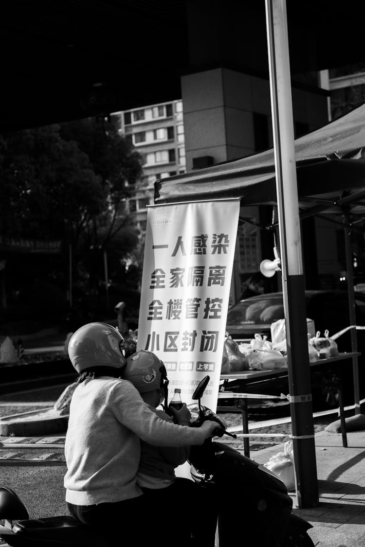 Couple In Helmets On Motorbike Reading Banner