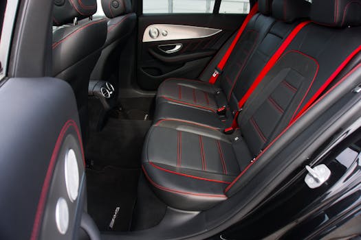 Interior view of a luxury car featuring leather seats with red trim, emphasizing comfort and modern design.
