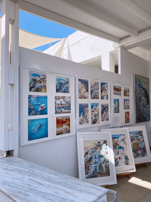 Free Art gallery showcasing framed paintings of Greek islands with vibrant blue and white colors. Stock Photo