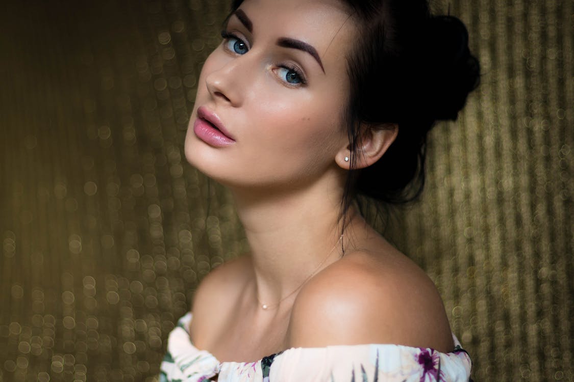 Woman Wearing White, Purple, and Green Floral Off-shoulder Top Standing Beside Brown Background